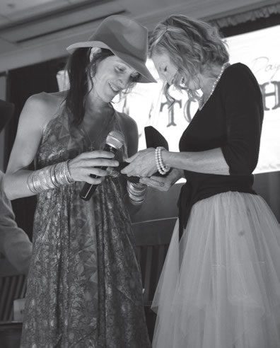 Crested Butte’s Kyleena Falzone (left), a breast cancer survivor, receives a Jimmy Clark commemorative buckle.